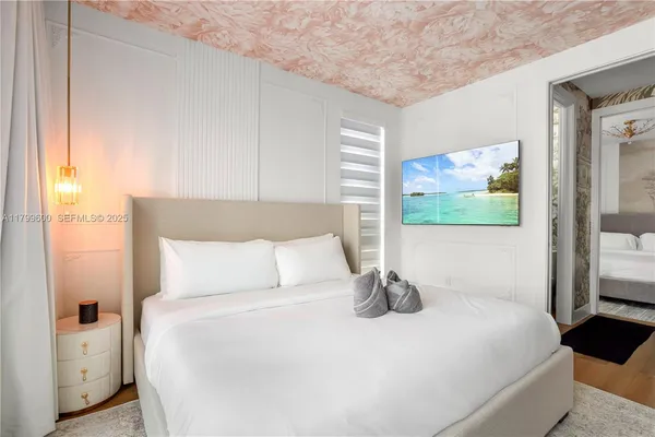 a large white bed sitting in a room next to a window