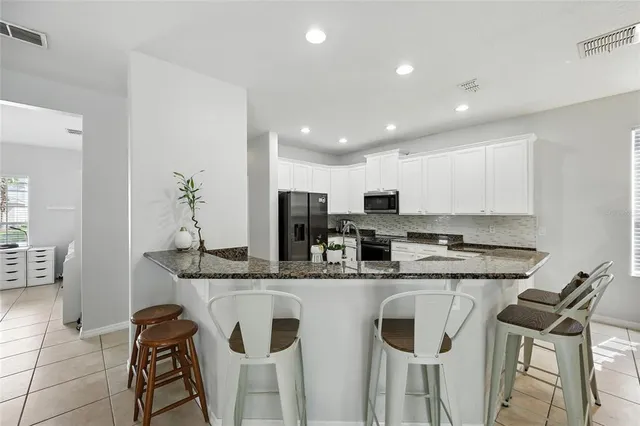 a kitchen with granite countertop a refrigerator and a stove top oven