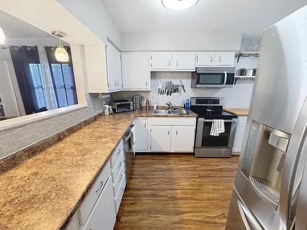 a large kitchen with stainless steel appliances granite countertop a stove top oven a sink dishwasher and a refrigerator