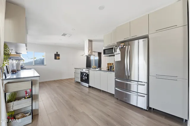 a kitchen with stainless steel appliances a refrigerator and wooden floor