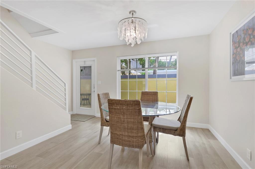 230 3rd Avenue South, Unit 4 Naples, FL 34102 - Photo 5 of 22 a view of a dining room with furniture a chandelier and wooden floor