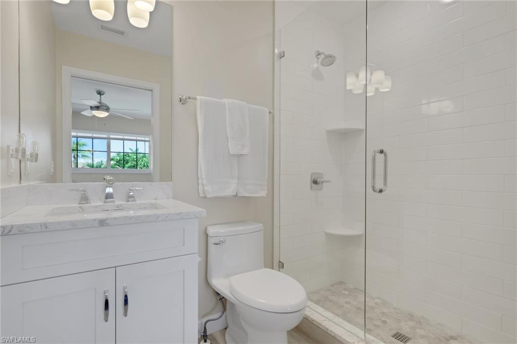 230 3rd Avenue South, Unit 4 Naples, FL 34102 - Photo 10 of 22 a bathroom with a toilet a sink a mirror and vanity