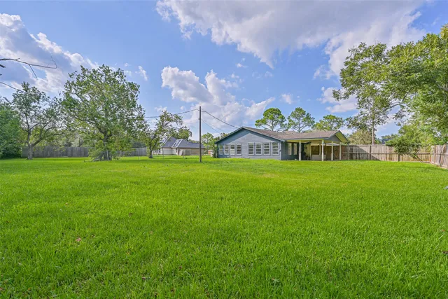 a view of a big house with a big yard and large trees
