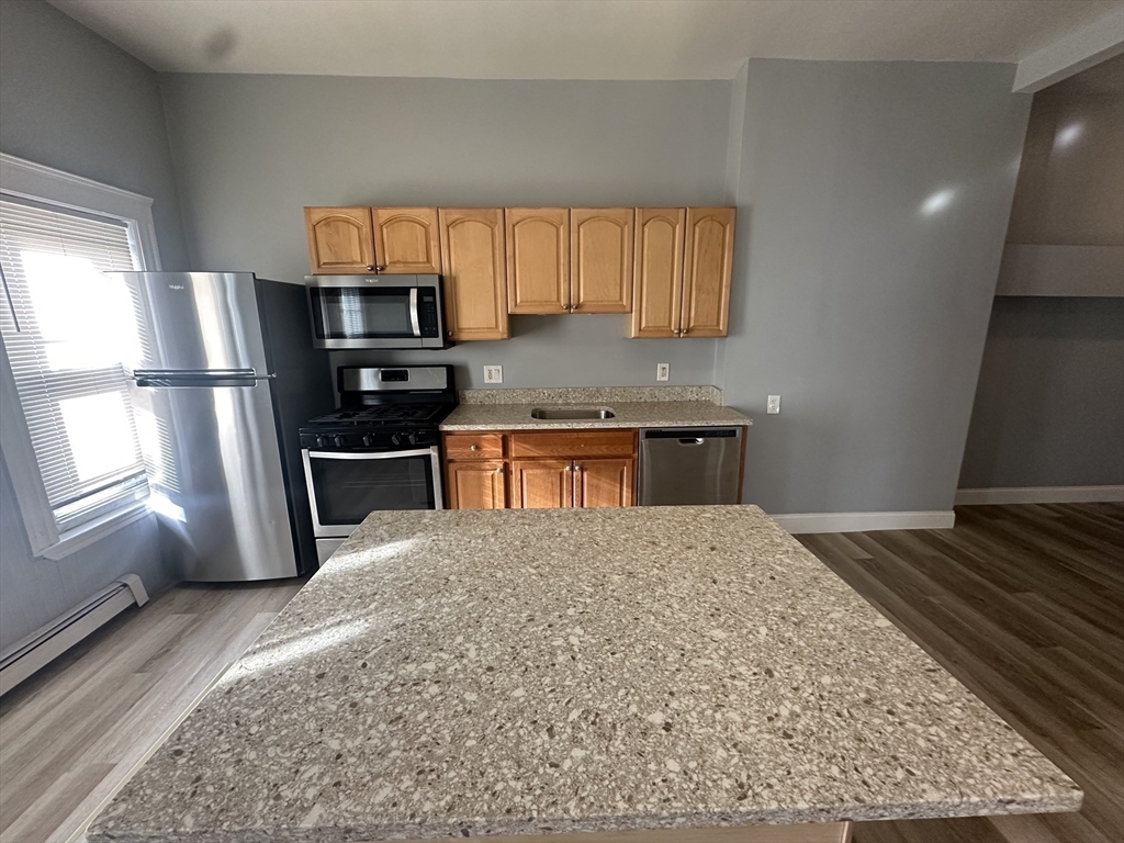 118 Gladstone Street, Unit B Boston, MA 02128 - Photo 3 of 16 a kitchen with stainless steel appliances granite countertop a sink stove and refrigerator