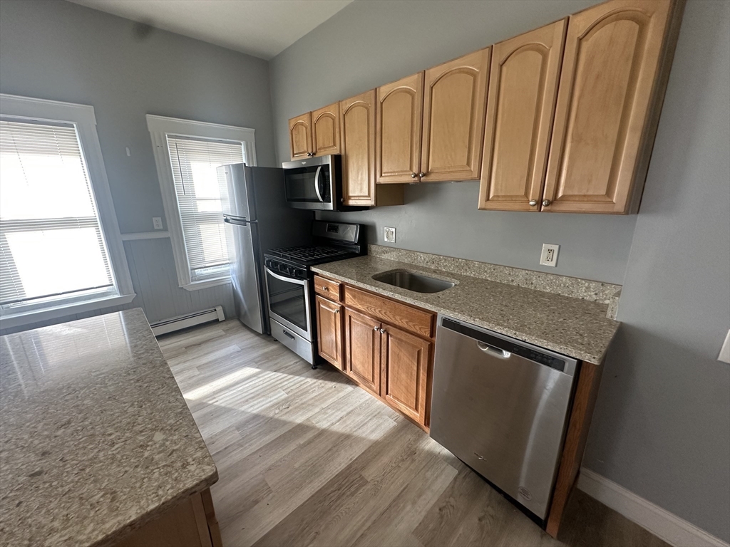 118 Gladstone Street, Unit B Boston, MA 02128 - Photo 5 of 16 a kitchen with stainless steel appliances granite countertop a stove a sink dishwasher and a refrigerator