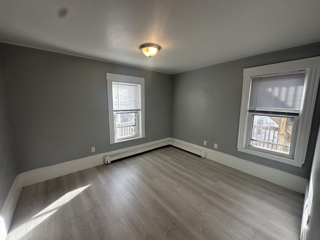 118 Gladstone Street, Unit B Boston, MA 02128 - Photo 7 of 16 an empty room with wooden floor and windows