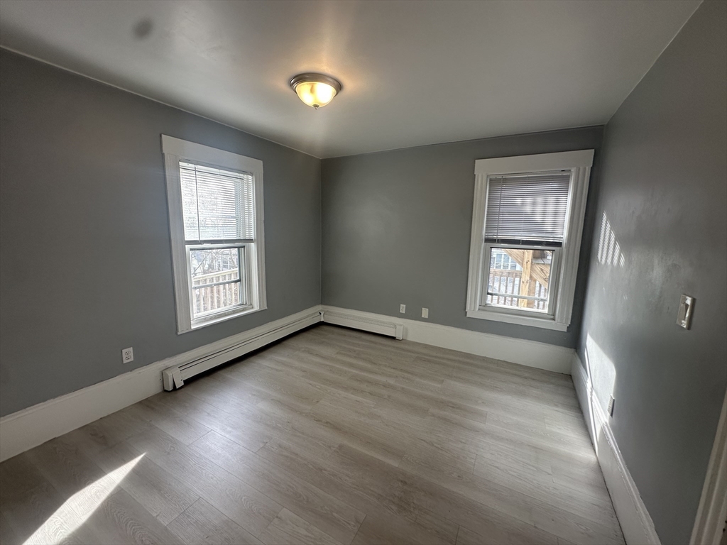 118 Gladstone Street, Unit B Boston, MA 02128 - Photo 8 of 16 an empty room with wooden floor and windows