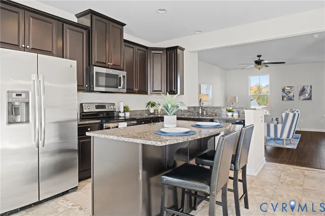 a kitchen with stainless steel appliances granite countertop a dining table chairs refrigerator and microwave