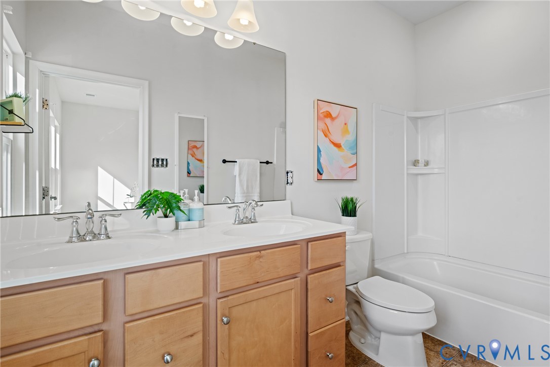 7849 Chasing Lane Richmond, VA 23237 - Photo 21 of 29 Full bathroom with double vanity, dark tile patter
