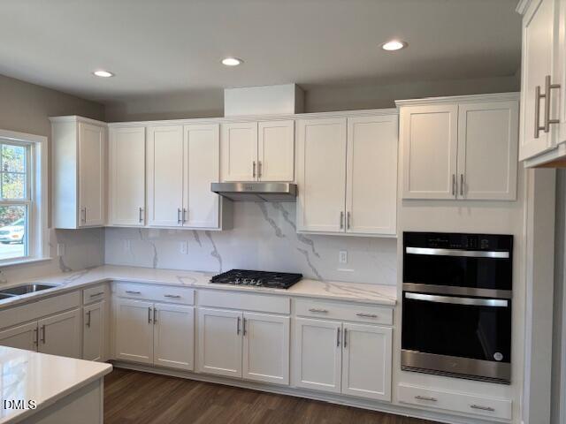 a kitchen with granite countertop white cabinets and stainless steel appliances