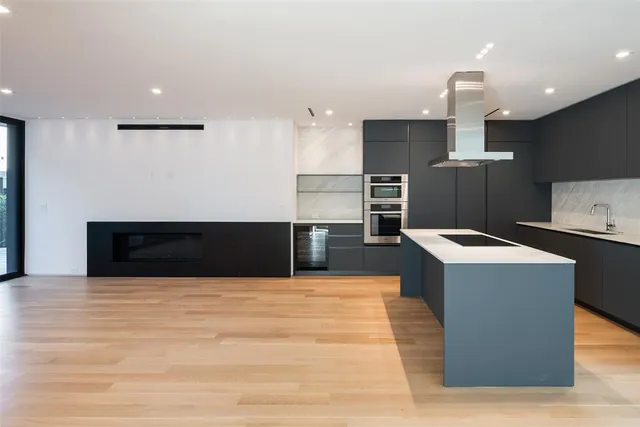 a large kitchen with stainless steel appliances a large counter top and a wooden floors