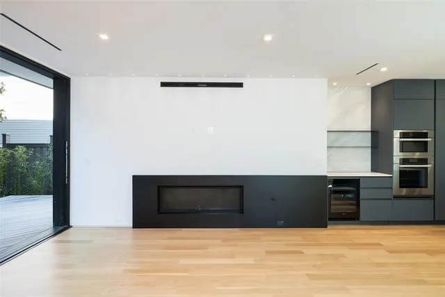 a view of an empty room with kitchen and a window