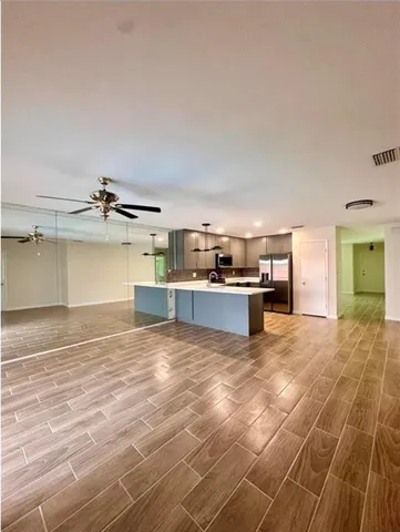 a view of kitchen and empty room with windows