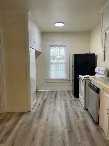 a view of a kitchen with wooden floor and electronic appliances