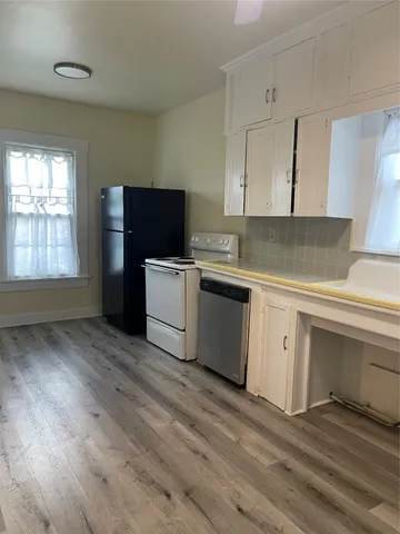 a kitchen with stainless steel appliances a white stove top oven cabinets and a window
