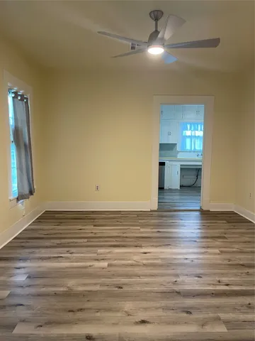 a view of empty room with wooden floor and fan