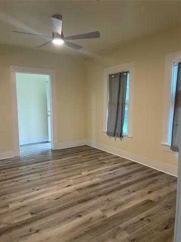 a view of an empty room with window and wooden floor