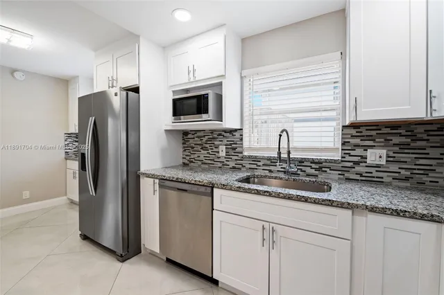 a kitchen with granite countertop white cabinets stainless steel appliances and a sink