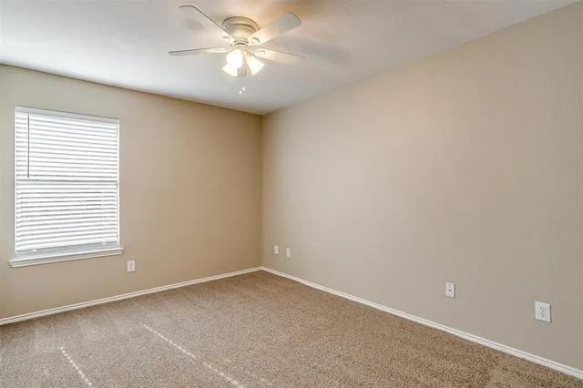 an empty room with a window and a fan