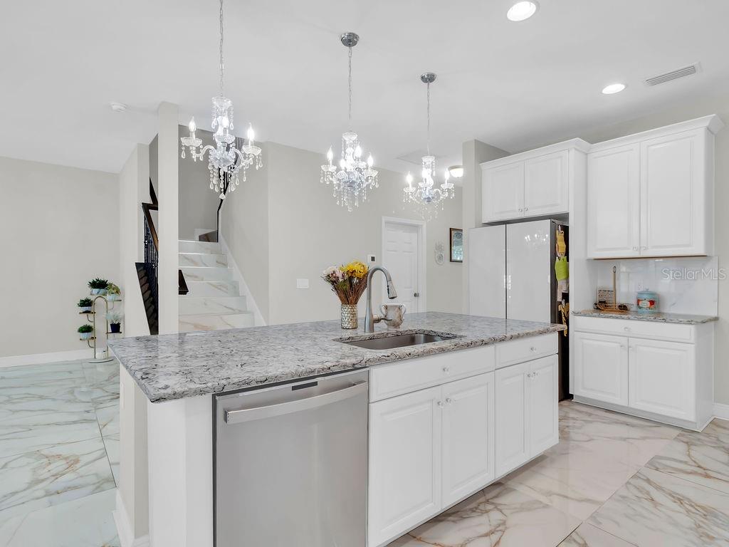 7406 Sweeter Tide Trail Wesley Chapel, FL 33545 - Photo 15 of 74 a kitchen with kitchen island granite countertop a white cabinets stove a sink and dishwasher