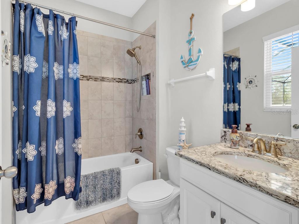 7406 Sweeter Tide Trail Wesley Chapel, FL 33545 - Photo 25 of 74 a bathroom with a granite countertop sink toilet and shower