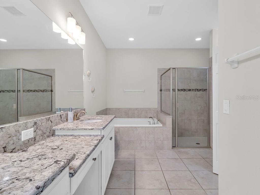 7406 Sweeter Tide Trail Wesley Chapel, FL 33545 - Photo 28 of 74 a bathroom with a granite countertop sink a toilet and shower