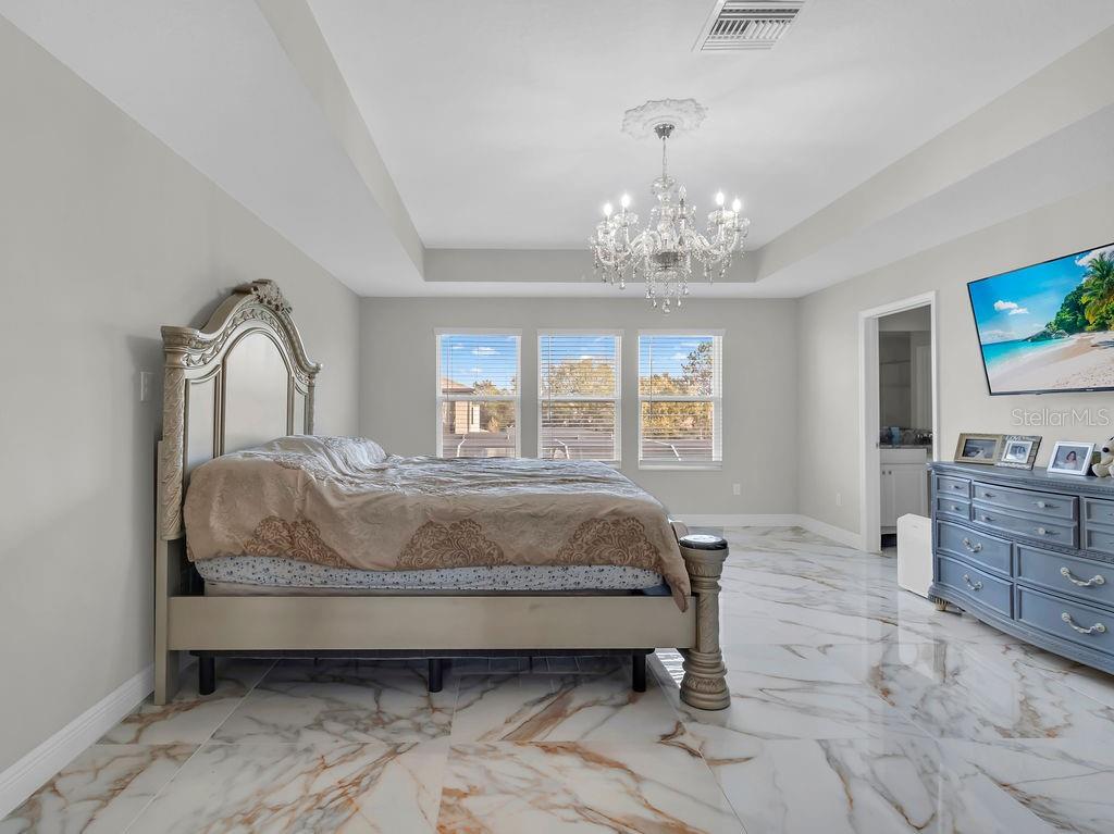 7406 Sweeter Tide Trail Wesley Chapel, FL 33545 - Photo 31 of 74 a spacious bedroom with a bed and a flat screen tv