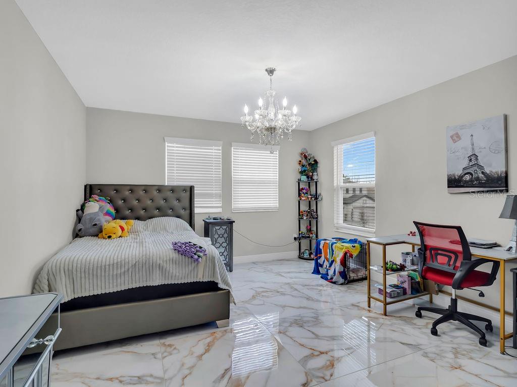 7406 Sweeter Tide Trail Wesley Chapel, FL 33545 - Photo 39 of 74 a bedroom with bed and a chandelier