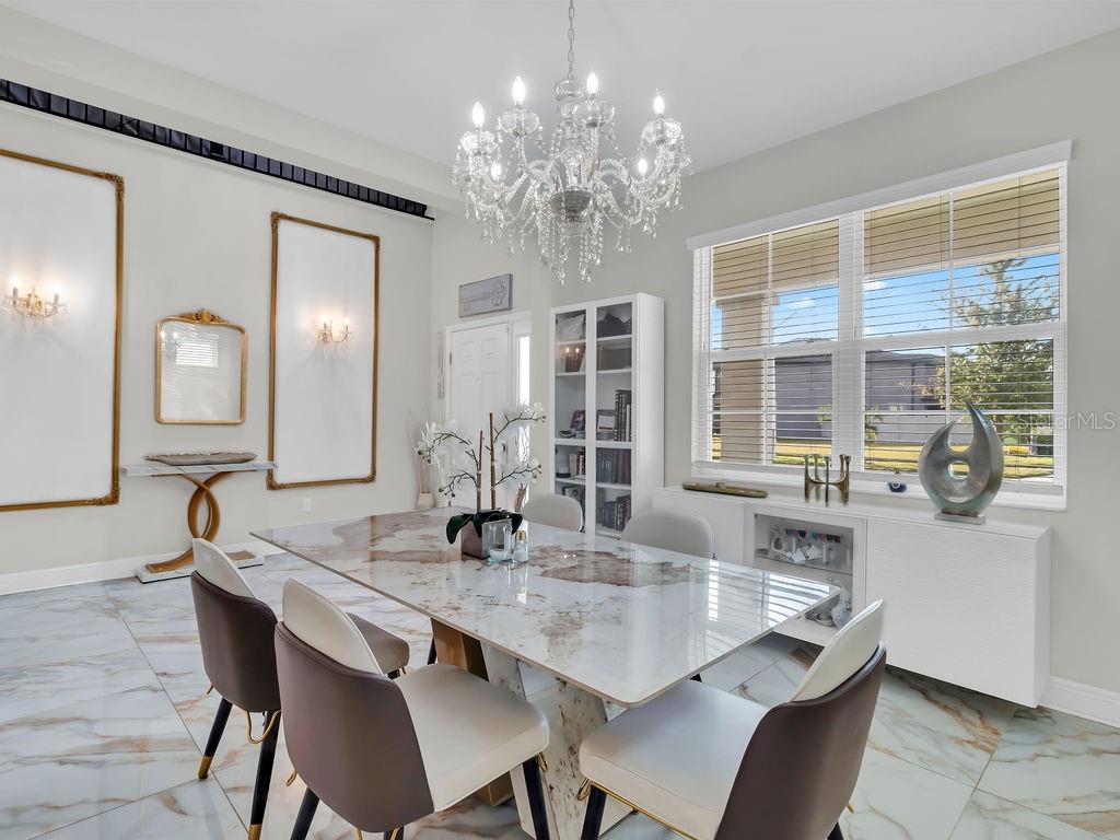 7406 Sweeter Tide Trail Wesley Chapel, FL 33545 - Photo 10 of 74 a dining room with wooden floor a chandelier a wooden table and chairs
