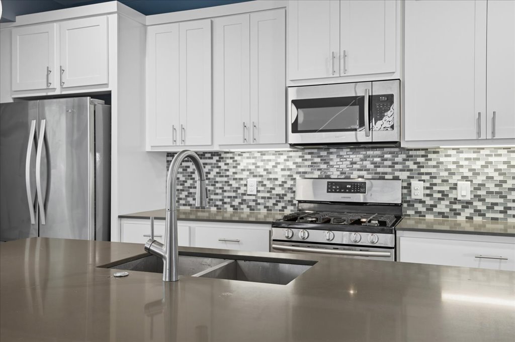 6902 Bennett Avenue, Unit B Austin, TX 78752 - Photo 9 of 27 Kitchen featuring stainless steel appliances, white cabinetry, tasteful backsplash, and dark stone countertops