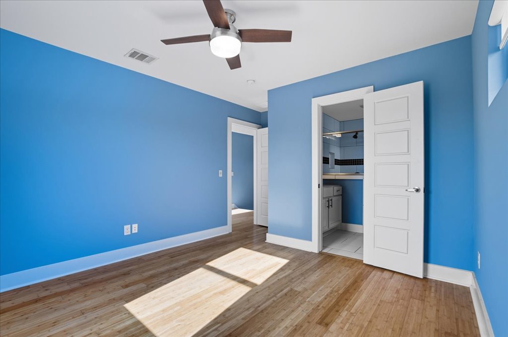 6902 Bennett Avenue, Unit B Austin, TX 78752 - Photo 4 of 27 Unfurnished bedroom featuring light wood-style flooring, ensuite bathroom, and ceiling fan
