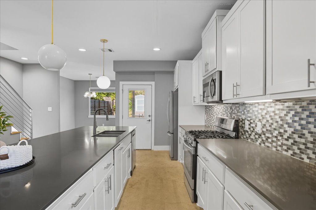 6902 Bennett Avenue, Unit B Austin, TX 78752 - Photo 8 of 27 Kitchen with stainless steel appliances, white cabinetry, hanging light fixtures, backsplash, and recessed lighting