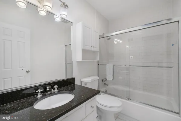 a bathroom with a granite countertop sink toilet a mirror and shower