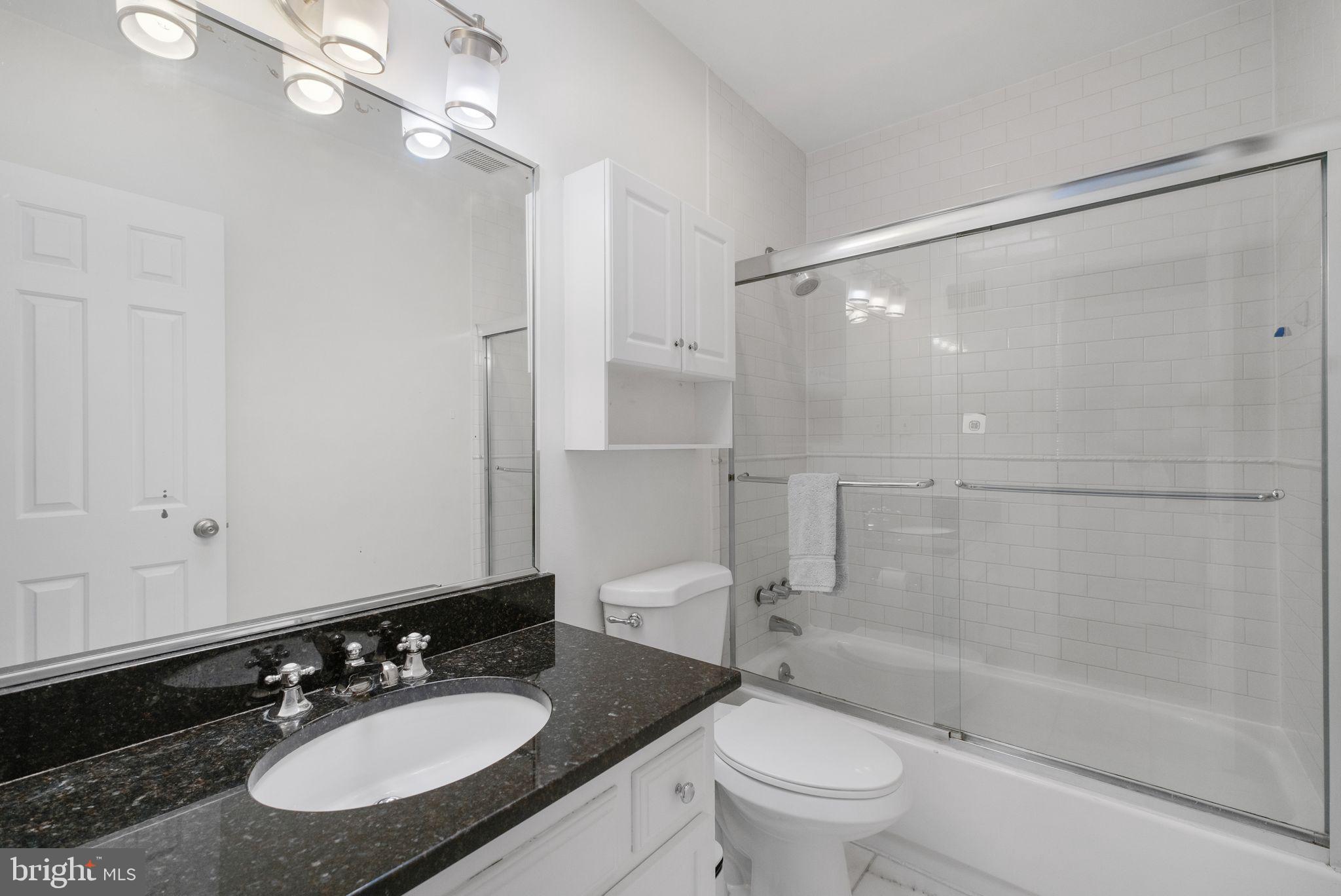 3256 Q Street Northwest Washington, DC 20007 - Photo 18 of 20 a bathroom with a granite countertop sink toilet a mirror and shower