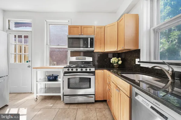 a kitchen with stainless steel appliances granite countertop a stove a sink and a microwave