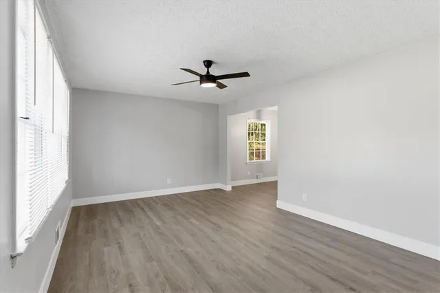 an empty room with wooden floor and windows