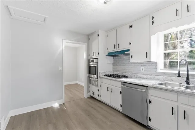 a kitchen with granite countertop a stove a sink and a refrigerator