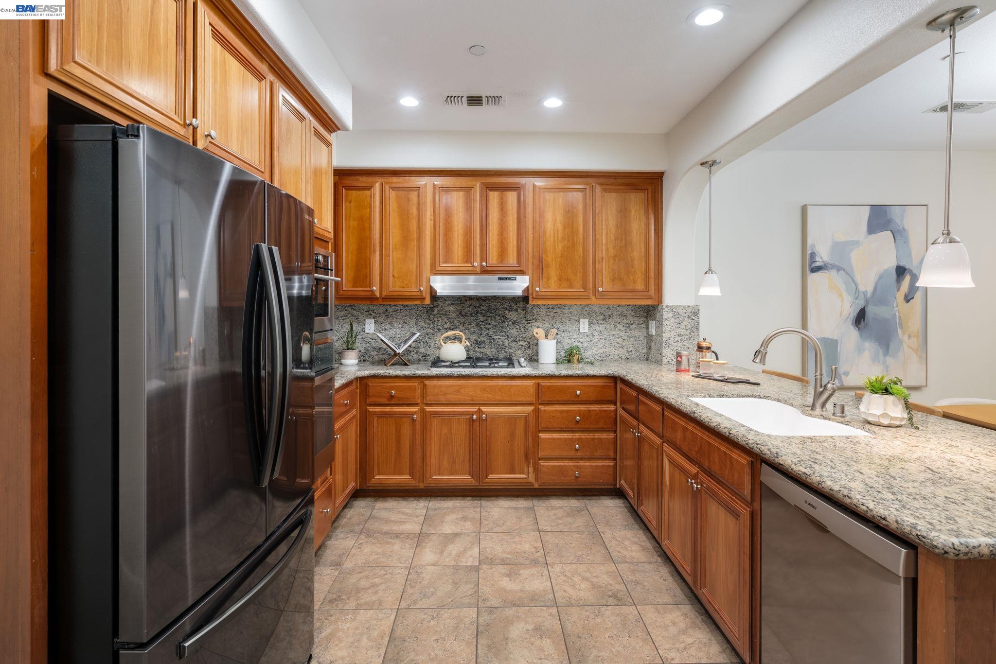 4653 Rimini Court Dublin, CA 94568 - Photo 15 of 44 a large kitchen with granite countertop a refrigerator and a sink