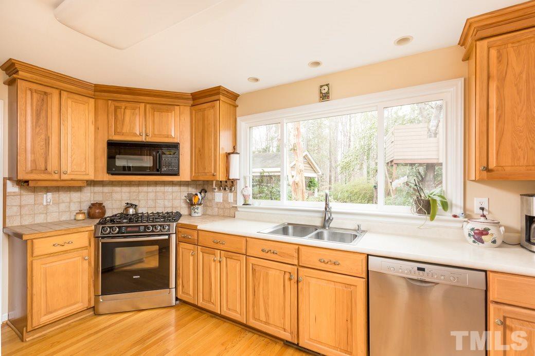 8632 Langtree Lane Raleigh, NC 27613 - Photo 6 of 25 a kitchen with granite countertop a sink appliances cabinets and a counter top space
