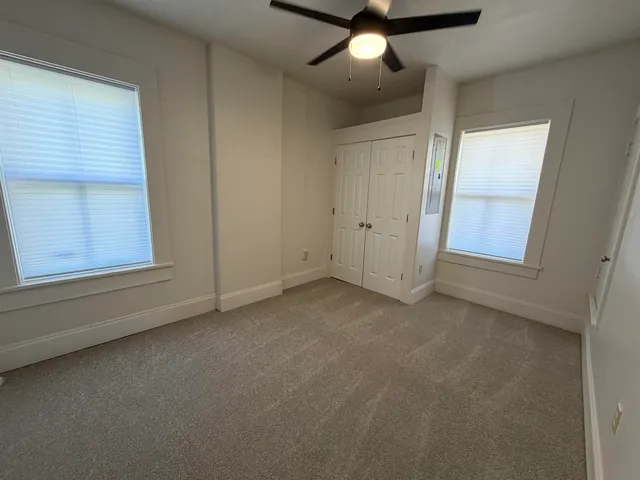 an empty room with a window and a ceiling fan