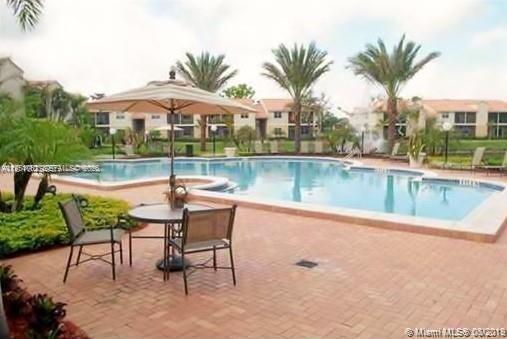 1235 Southwest 46th Avenue, Unit 711 Pompano Beach, FL 33069 - Photo 19 of 43 a view of a swimming pool with a table and chairs