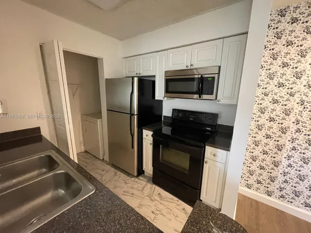 a kitchen with granite countertop a refrigerator and a sink