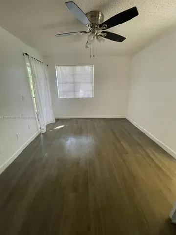an empty room with wooden floor fan and windows