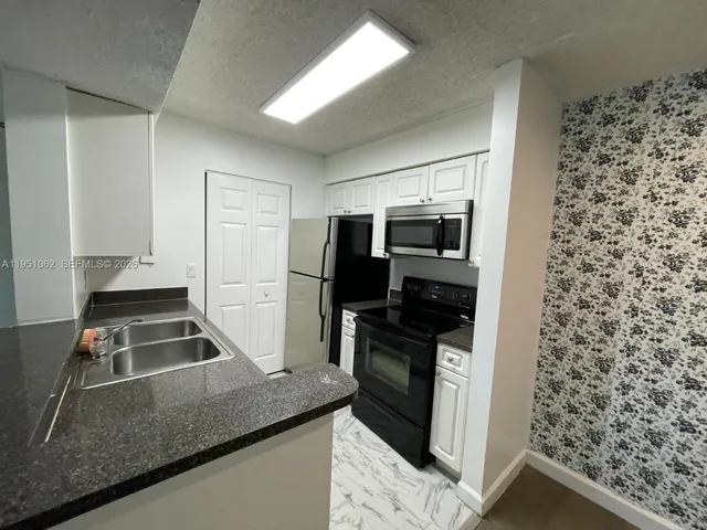 a kitchen with stainless steel appliances granite countertop a refrigerator and a stove