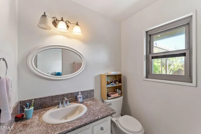 a bathroom with a granite countertop toilet a sink and a mirror