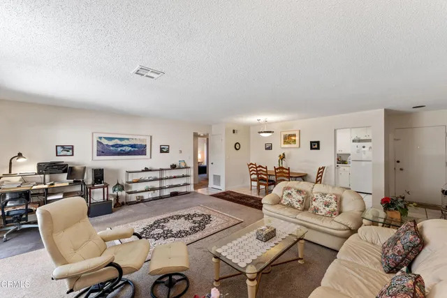 a living room with furniture kitchen view and a window