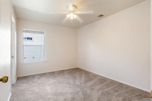 an empty room with a ceiling fan and a window