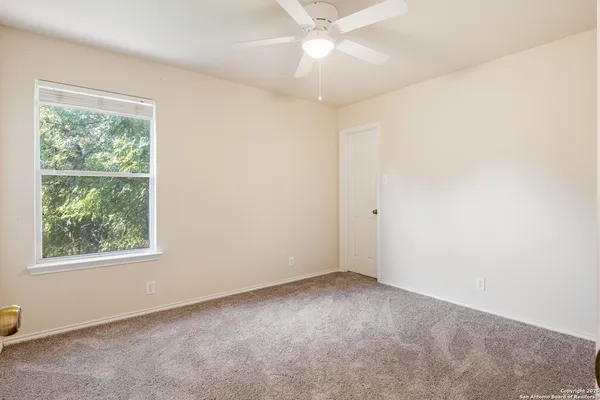 an empty room with a window and a fan