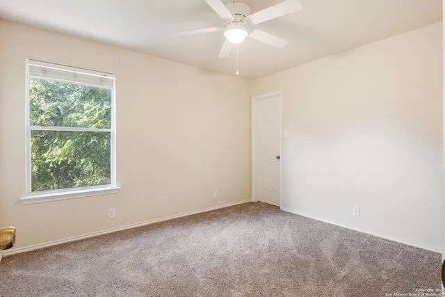 an empty room with a window and a fan