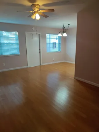 a view of an empty room with window and wooden floor
